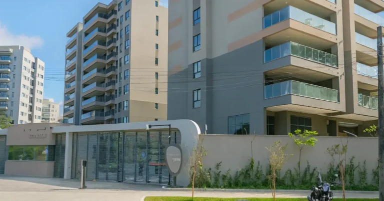 Entrada do residencial Concept Cyrela com portaria moderna, prédios altos e varandas envidraçadas em um dia ensolarado.